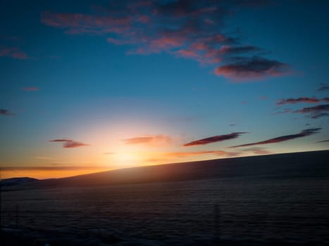 The sun is setting over a body of water. Photo of a beautiful sunset over a serene Icelandic body of water