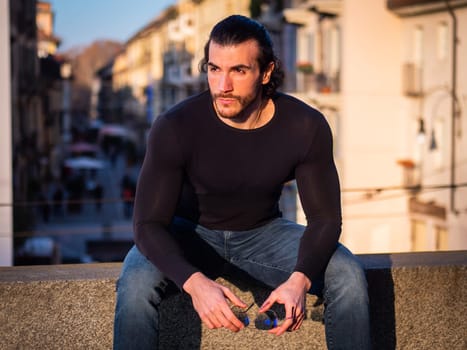 A man sitting on a ledge with his hands on his knees