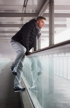 A man leaning against a glass wall in a building