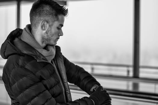 A man sitting on a bench looking at his wrist watch in a black and white photo