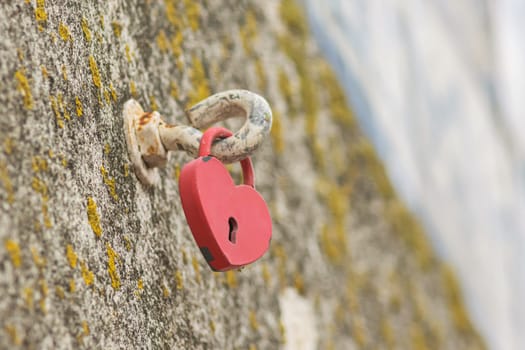 A heart-shaped lock is suspended on a hook. Mid shot