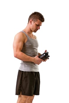 A man in a tank top is holding a shaker with a protein shake or beverage