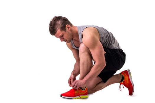 A man tying his shoelaces while squatting