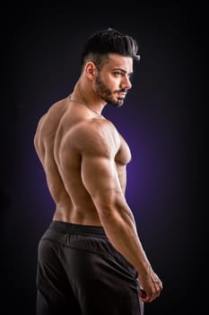 A shirtless man with no shirt posing for a picture, against black background in studio