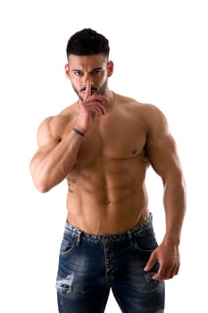 A shirtless man gesturing hush or silence, with finger on his lips and looking at the camera