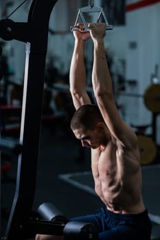 A man does a chest pulldown in the gym