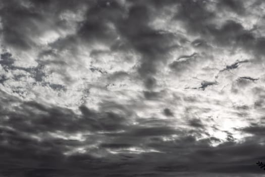The light of the sun at sunrise through black and white thick clouds. Stormy weather.