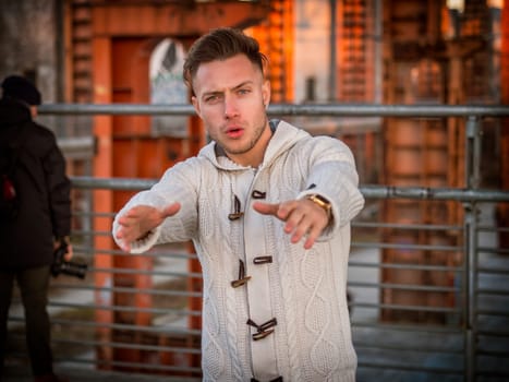 Photo of a man with captivating blue eyes pointing at something while wearing a white sweater