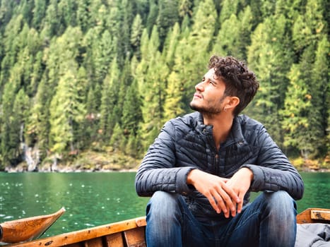 A man sitting in a boat on a lake. Photo of a man peacefully enjoying the serenity of a scenic lake in the beautiful Italian Dolomites