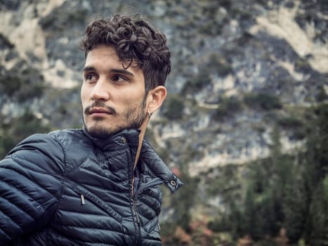 A man with curly hair wearing a black jacket. Photo of a stylish man with curly hair wearing a black jacket against the stunning backdrop of the Dolomites in Italy