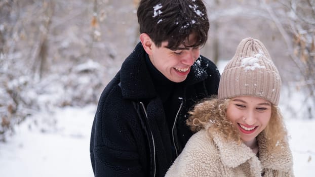 A young couple walks in the park in winter. Guy and girl hugging outdoors