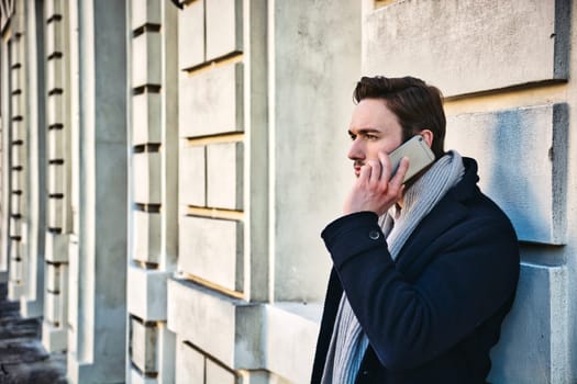 A man leaning against a wall talking on a cell phone