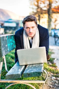 A man sitting on a bench with a laptop