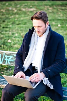 A man sitting on a bench with a laptop