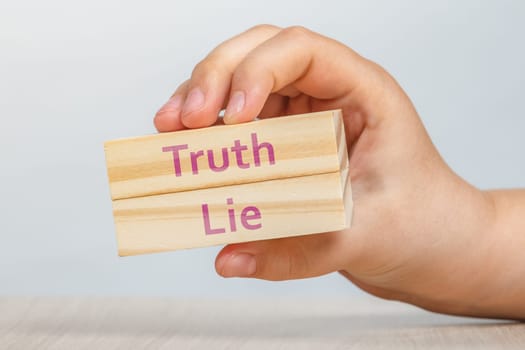 Truth and lie. A hand holds two wooden cubes with the inscriptions TRUTH and LIE To be inserted into a design or project. High quality photo