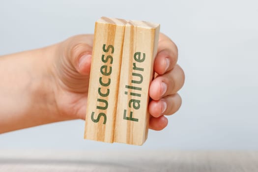 Success and failure. A hand holds two wooden cubes with the inscriptions SUCCESS and FAILURE For insertion into a design or project. High quality photo
