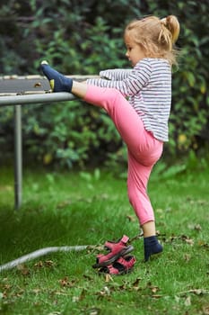 Curious child climbs on a trampoline in the evening garden in Denmark.