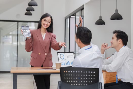 Professional businesswomen presenting to colleagues in conference room explaining corporate earnings..