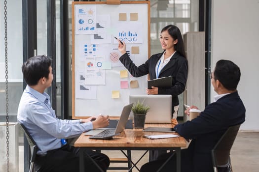 Businesswoman presenting data analysis on a board to her colleagues in the company.