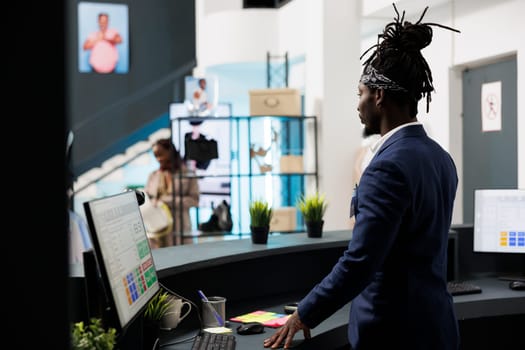 Shopping store worker standing at cash register, analyzing financial profit on computer in shopping centre. Stylish employee preparing fashionable clothes for clients packages. Fashion concept