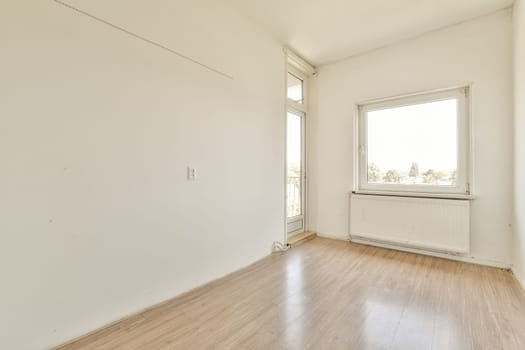 an empty room with wood flooring and white paint on the walls, there is a window in the corner