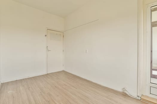 an empty room with white walls and wood flooring on one side, there is a door in the corner