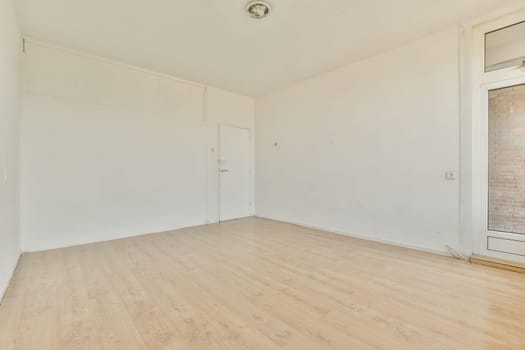 an empty room with white walls and wood flooring on the right, there is a brick wall in the background