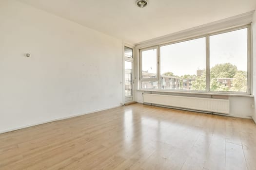 an empty living room with wood flooring and large windows looking out onto the street in front of the house