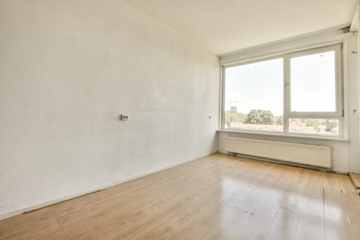 an empty room with wood floor and large window looking out onto the city skyline in the distance is visible on the wall