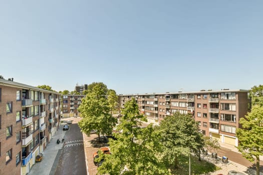 an apartment complex with trees and cars parked in the parking lot, taken from above on a clear blue sky day