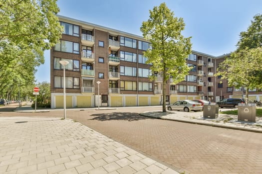 an apartment building with cars parked on the street in front of it and trees lining the side of the road