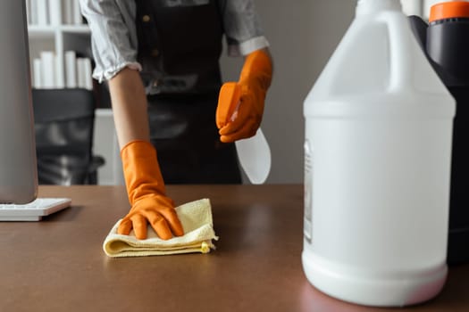 Woman maid cleaning and wiping the table with microfiber cloth in office.