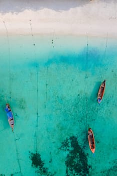 Koh Lipe Island Southern Thailand with turqouse colored ocean and white sandy beach at Ko Lipe. Longtail boats on the beach from above seen from a drone aerial view