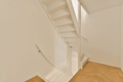 a white room with wood flooring and a staircase leading up to the second floor, which is also empty