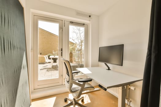 a room with a desk, chair and television set in front of a sliding glass door that opens onto the patio