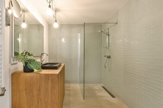 a bathroom with green tiles on the walls and wood vanity in the shower stall is next to the bathtub