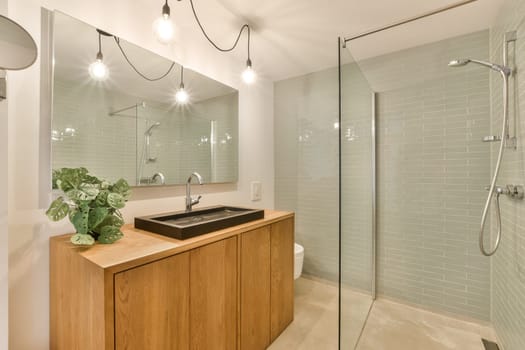 a bathroom with a sink, mirror and shower head mounted on the wall next to a wooden cabinet under it