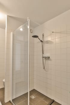a bathroom with tiled floor and shower stall in the corner, there is a glass door on the right side
