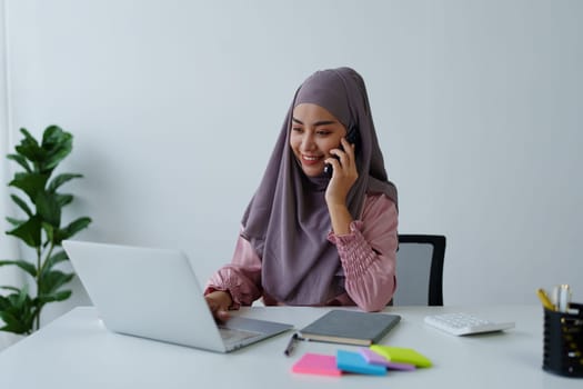 Muslim female employee Using the phone to talk to customers in the office