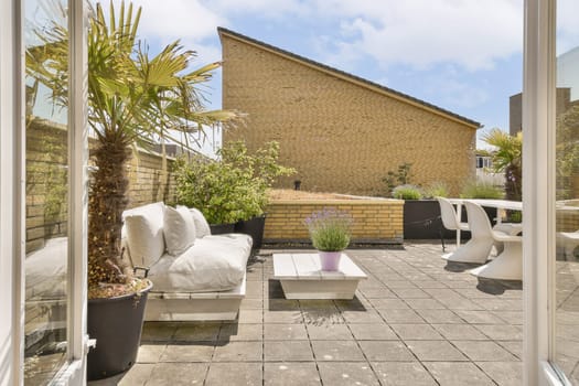 an outside area with furniture and plants in the fore - image is taken from inside, but no one can see it