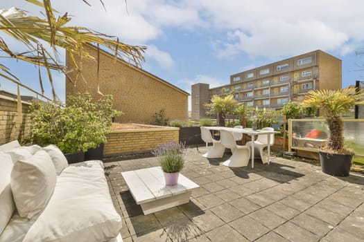 an outdoor patio area with furniture and potted plants on the ground in front of a brick wall, surrounded by trees