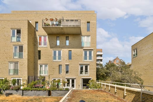 an apartment building that is very large and has many windows on the top, with plants growing in the yard below