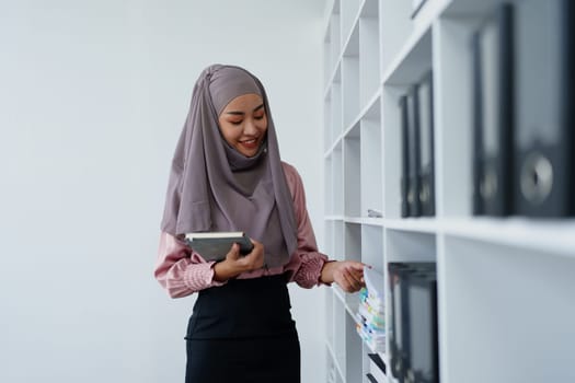 Muslim female employee Searching for documents in the office