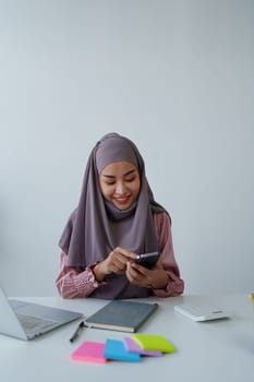 Muslim female employee Using the phone to talk to customers in the office