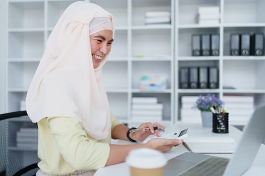 Muslim women use calculators, computers, and laptops to check their accounts at work