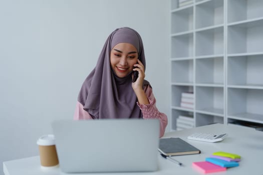 Muslim female employee Using the phone to talk to customers in the office