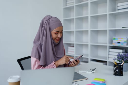 Muslim female employee Using the phone to talk to customers in the office