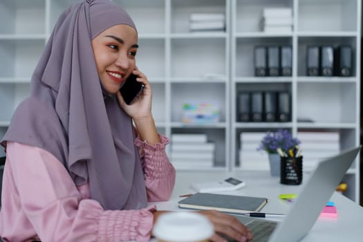 Muslim female employee Using the phone to talk to customers in the office