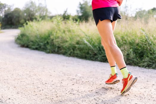 legs of an unrecognizable woman running in the countryside, concept of sport in nature and active lifestyle, copy space for text