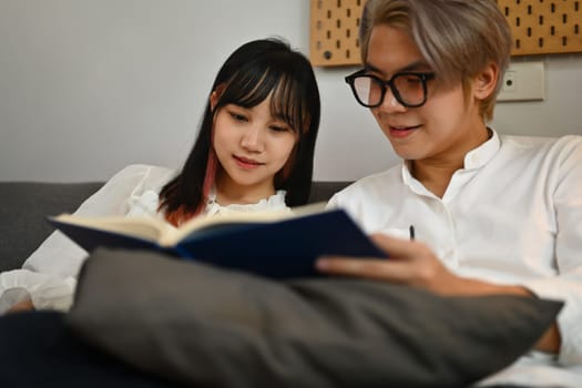 Asian young couple relaxing on couch spending weekend together at home.